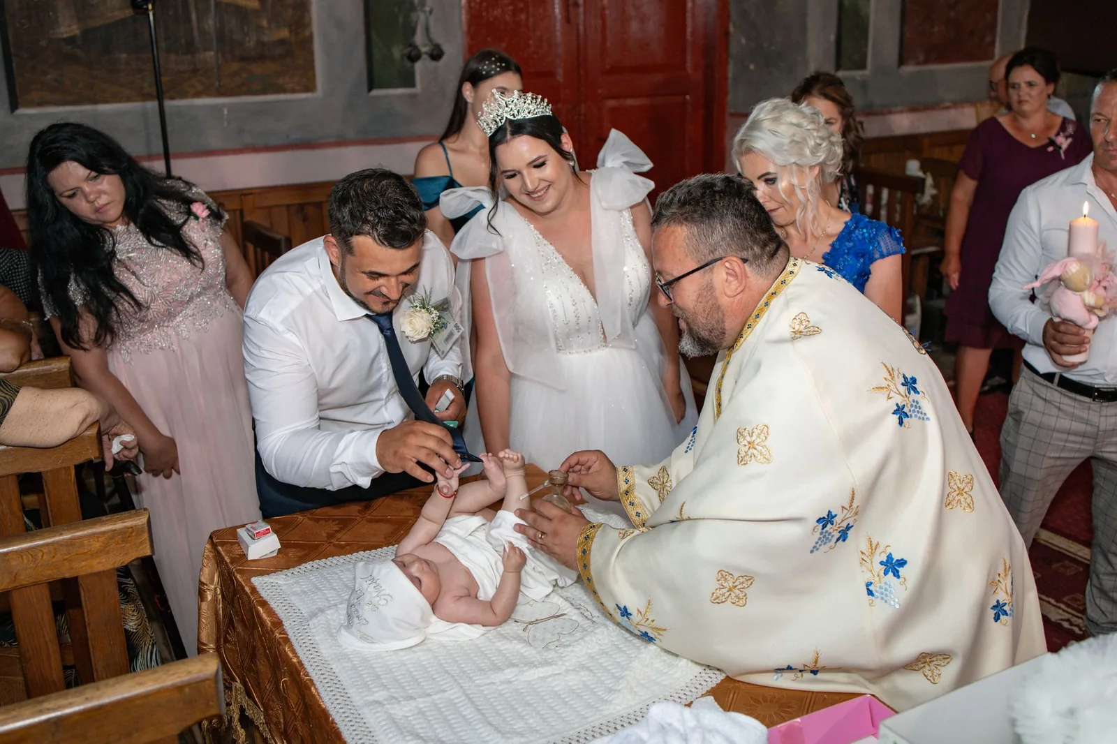 Ceremonie de botez într-o biserică, cu nașii și preotul