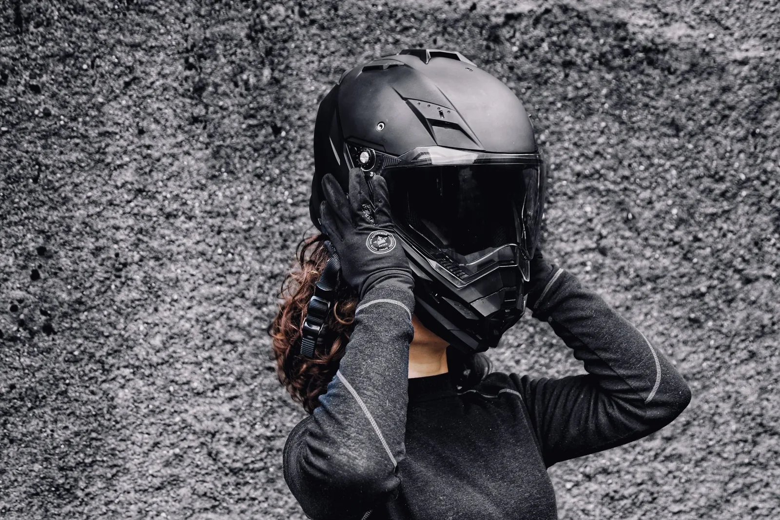 Motociclist punându-și casca, cu mănuși pe mâini