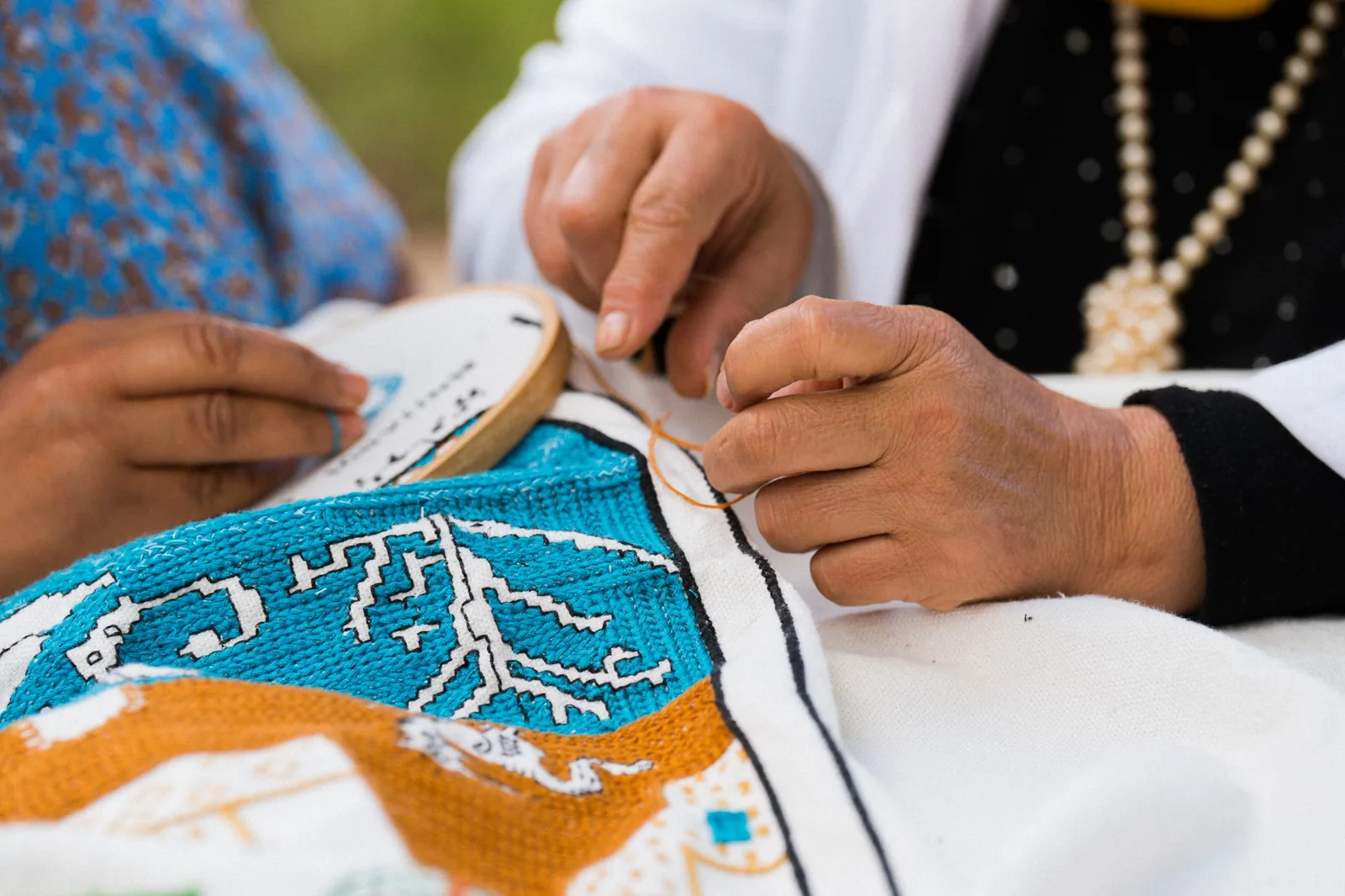 Mâini lucrând o broderie, detaliu de aproape