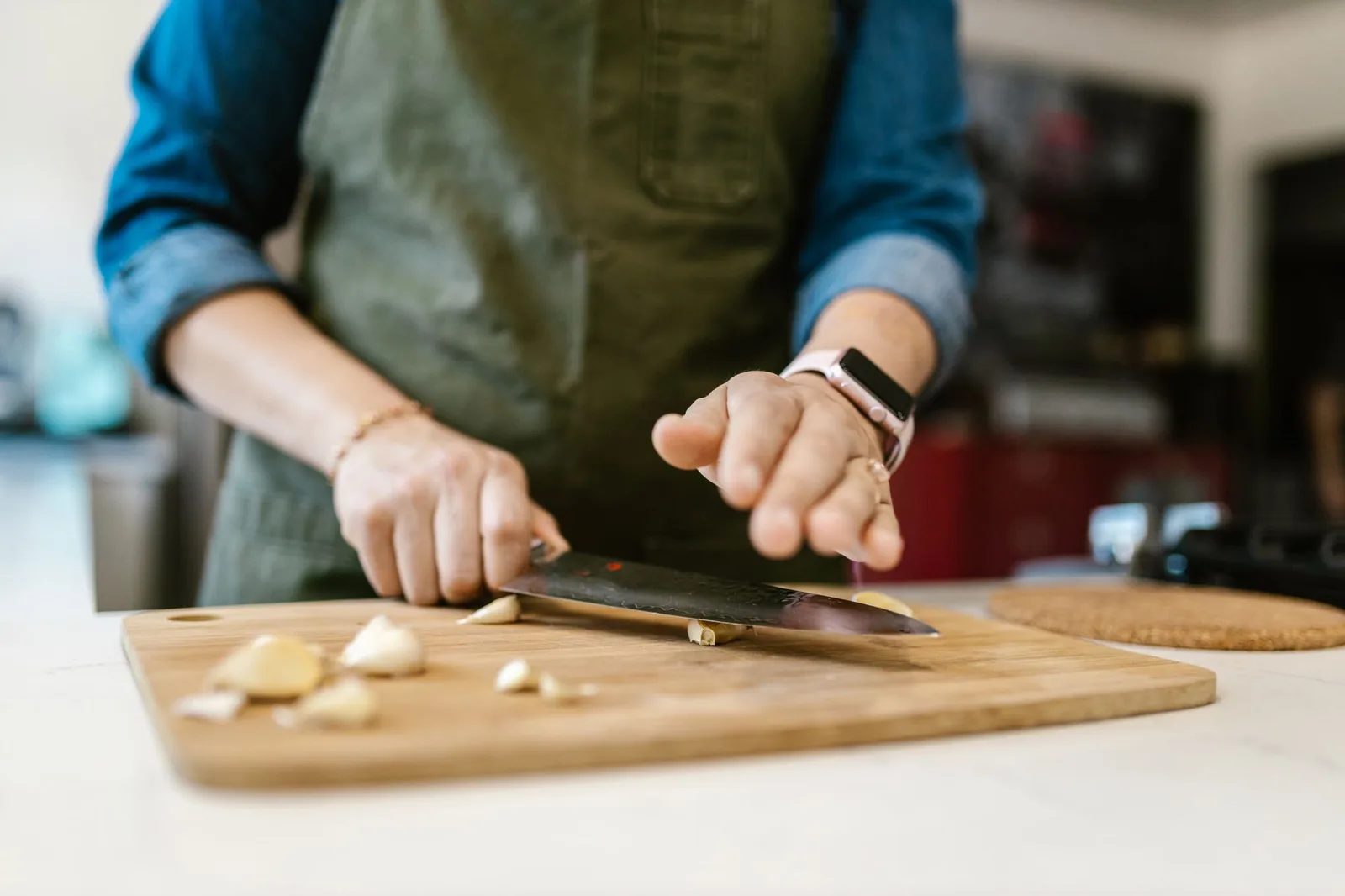 Mâini tăind pe un tocător, cu ingrediente în jur
