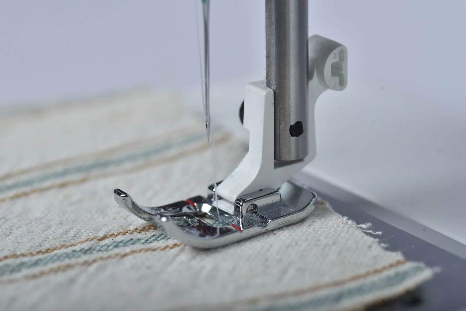 Mașină de broderie cosând un material, ac și fir în prim-plan