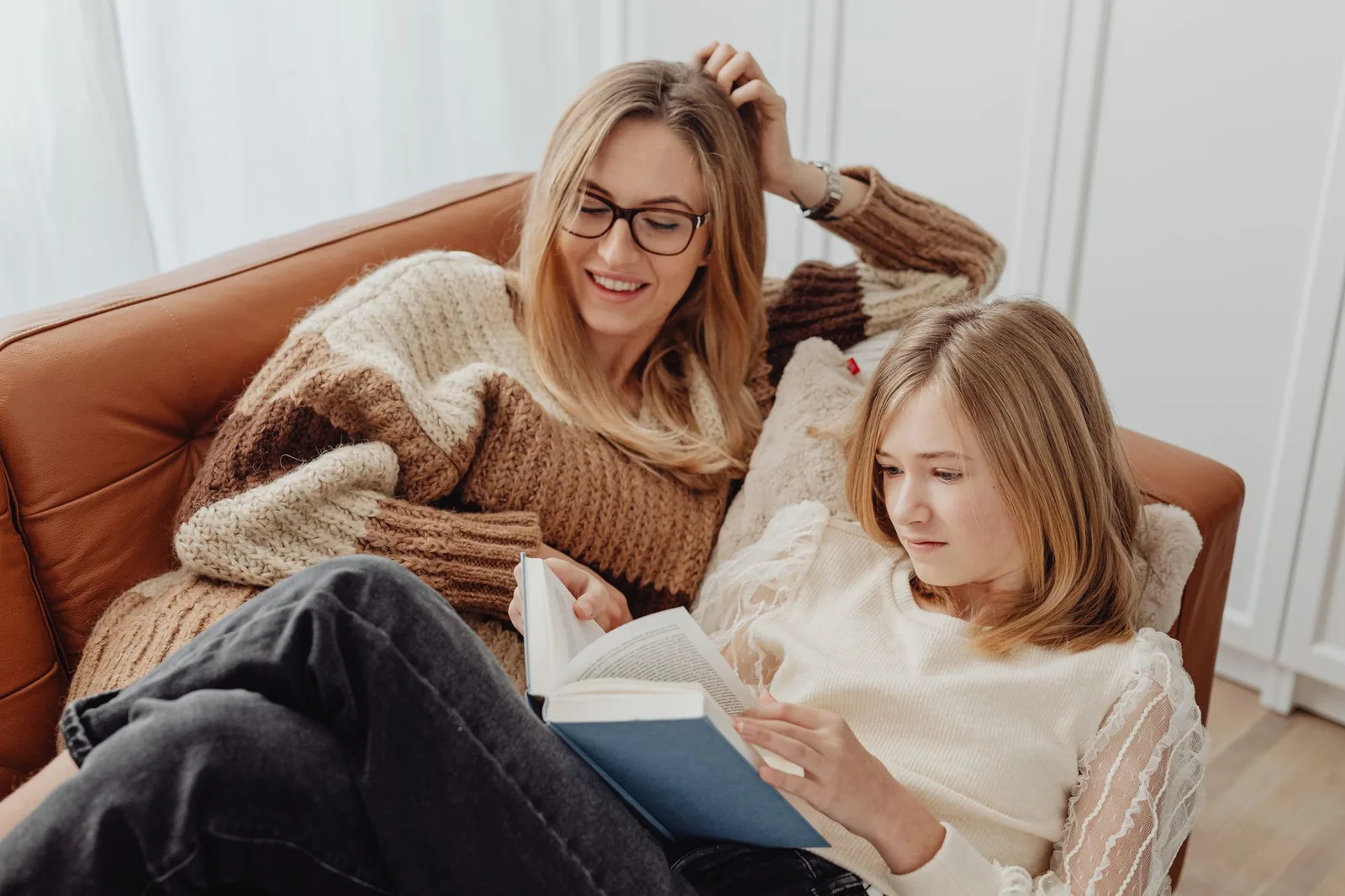 Părinte și adolescentă stând împreună pe canapea