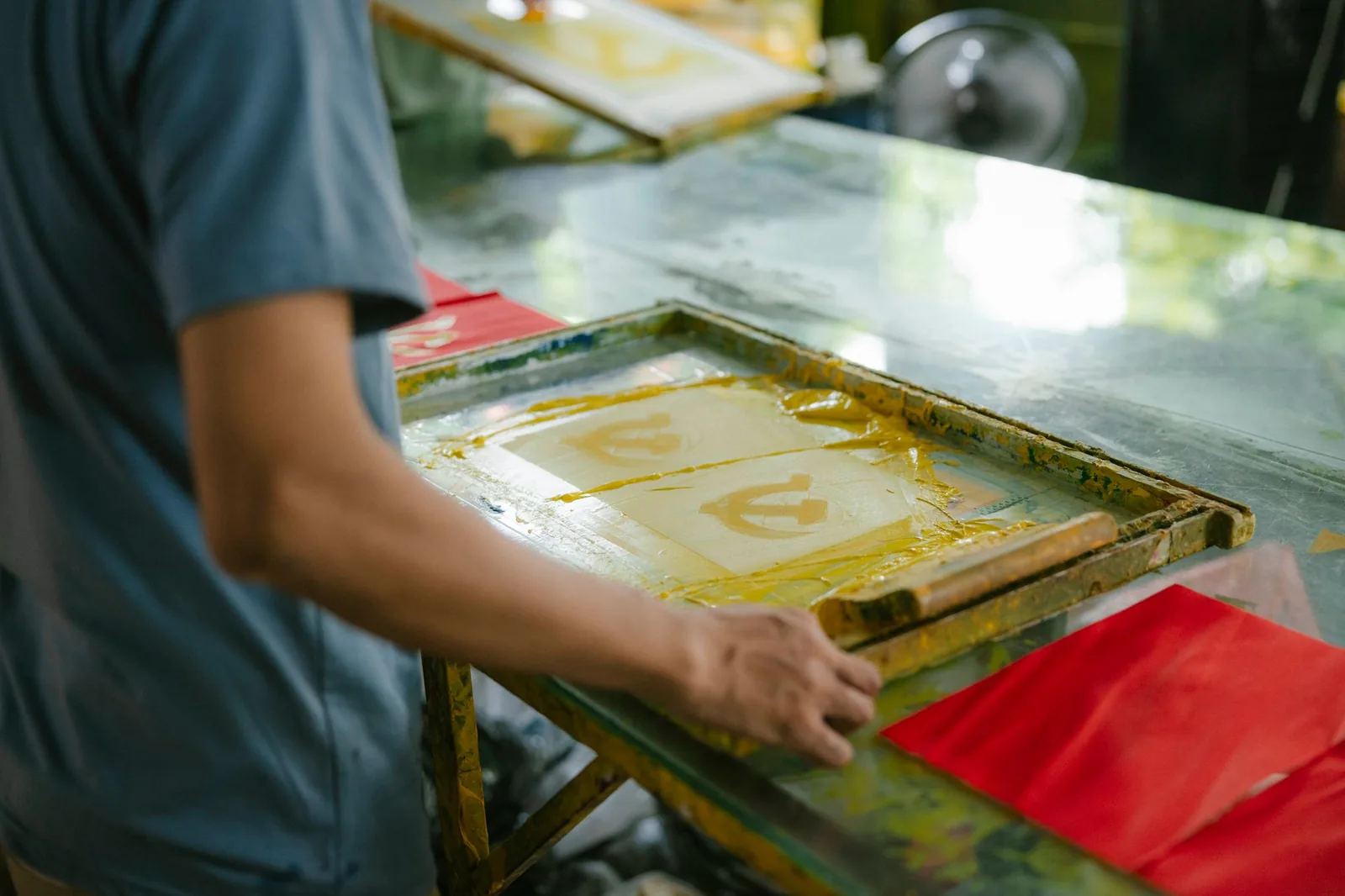 Atelier de serigrafie — cerneală întinsă cu racleta printr-o sită