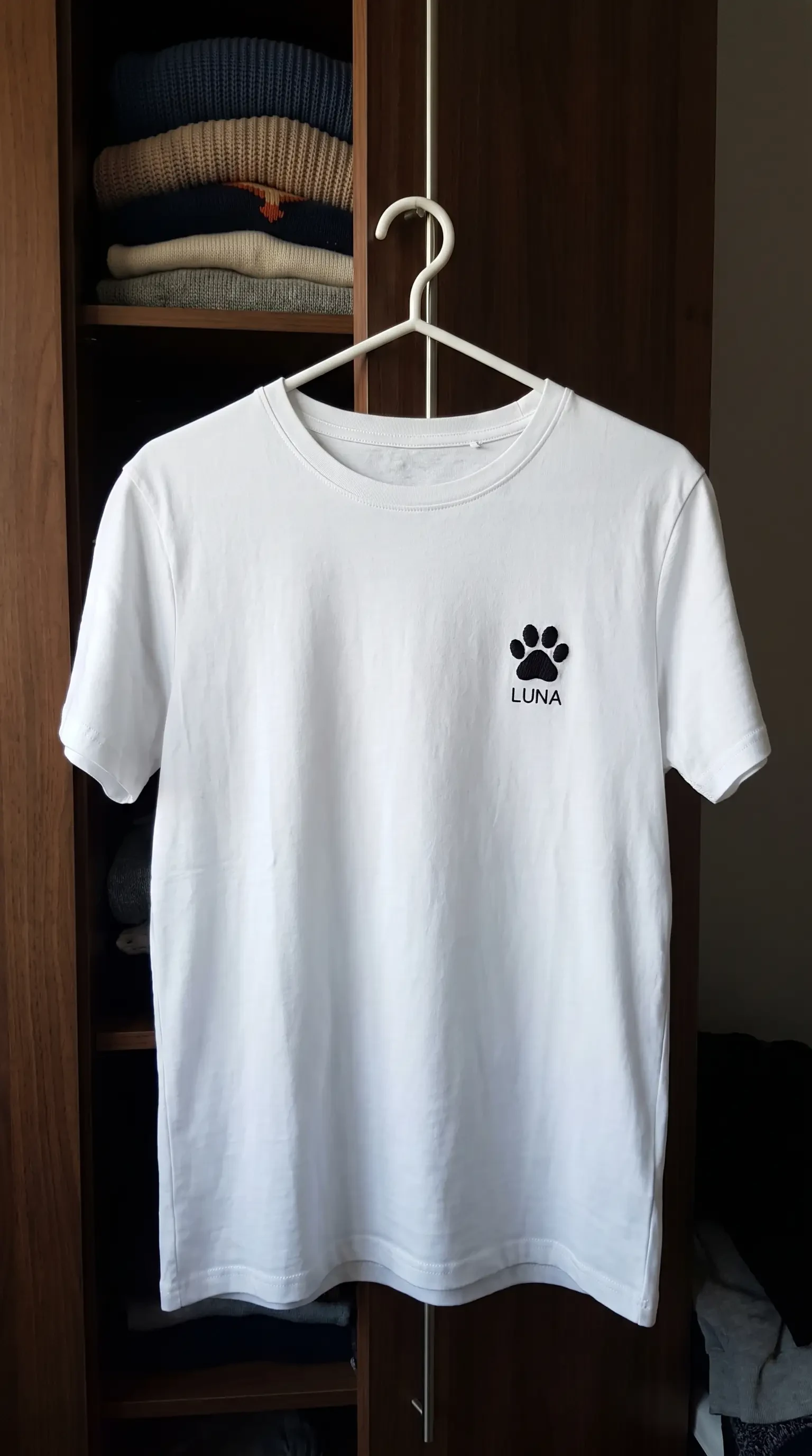 Tricou alb pe umeraș, cu o lăbuță brodată și numele LUNA dedesubt